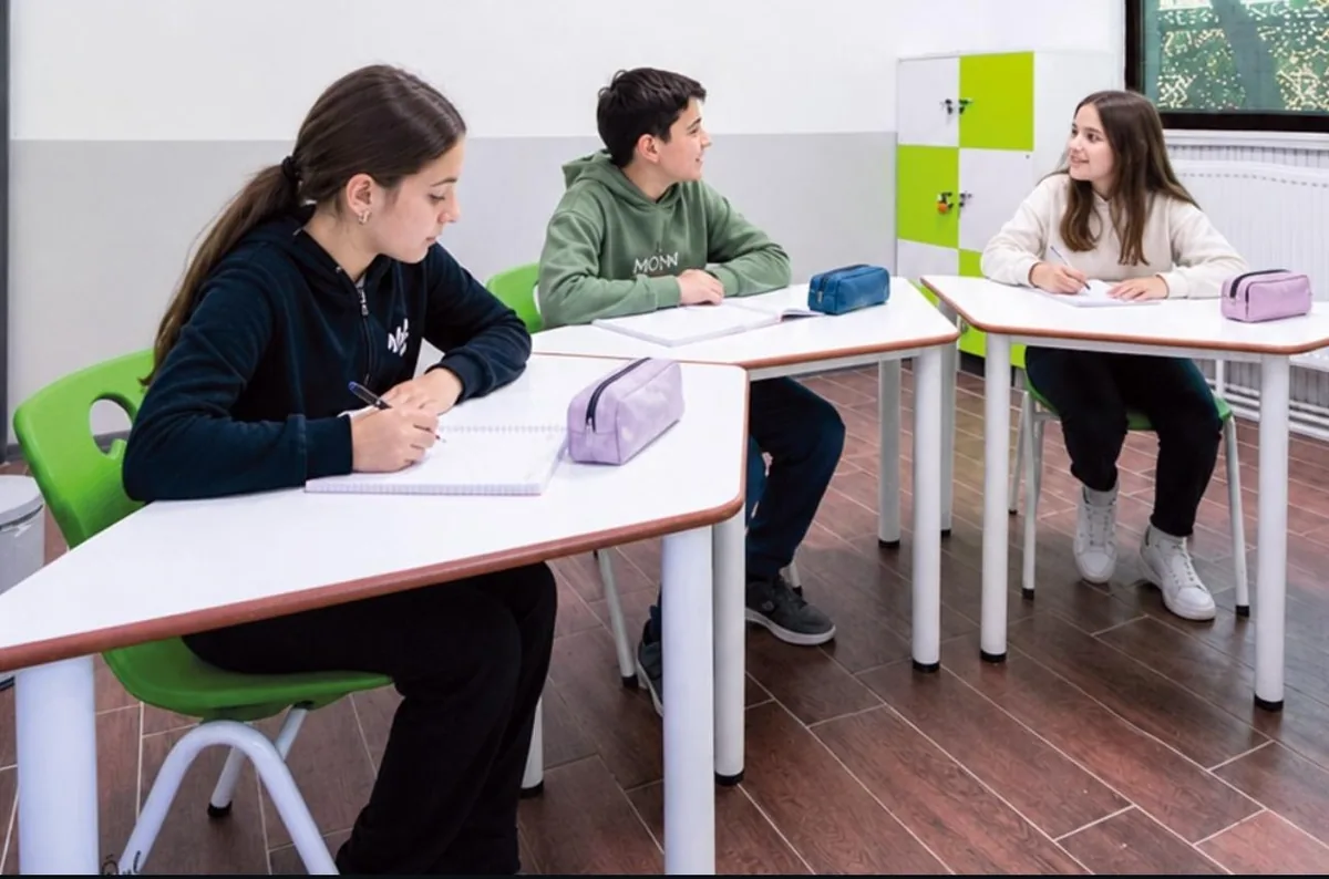 Üç öğrencinin ders yaptığı aydınlık sınıf